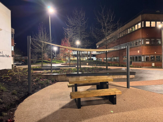 Outdoor seating surrounded by planting at Booths Park after dark.