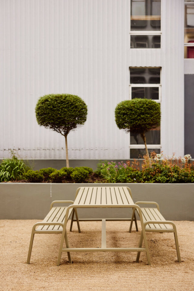 Outdoor tables beside planted borders at Riverside, Salford.