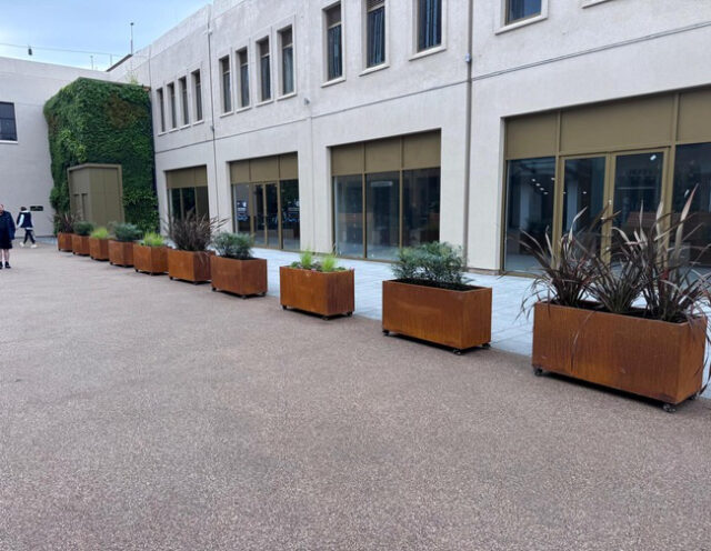 A row of planted Corten CORE PLANTERS along the pedestrian square.