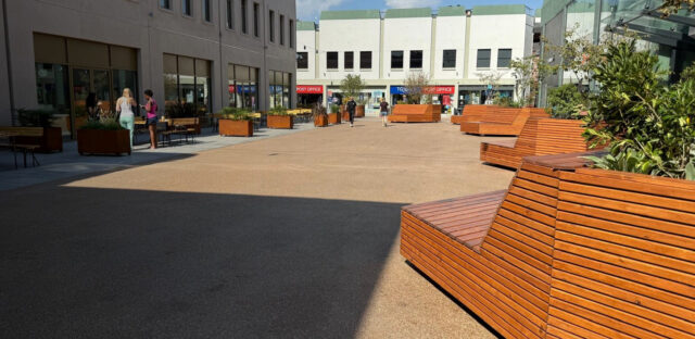 Corten planters and timber seating across the renewed square.